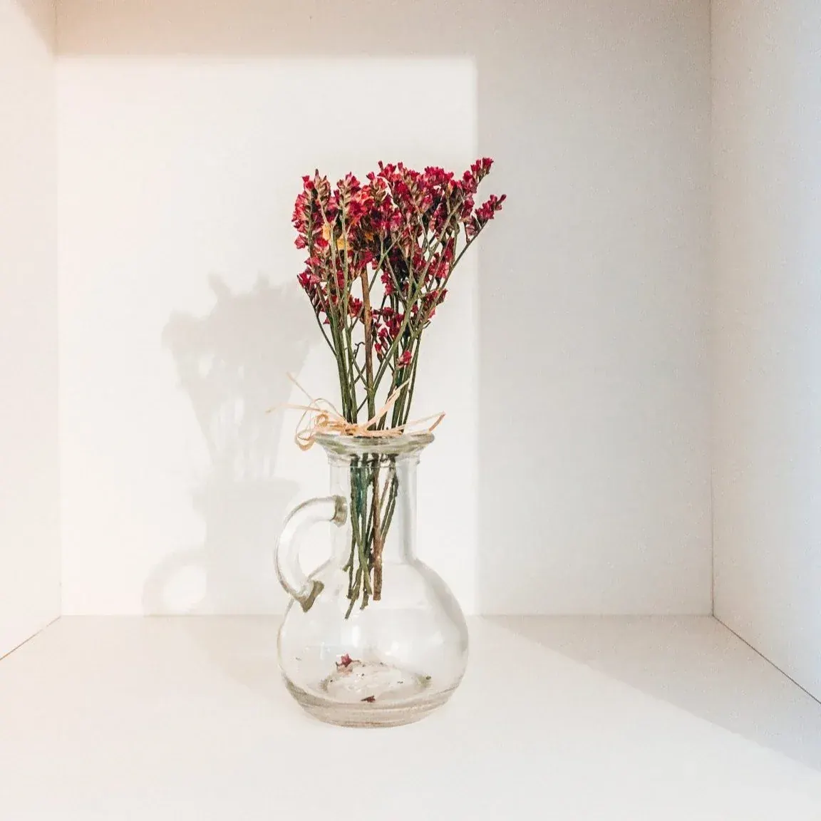 A reused glass oil container holding flowers as a vase